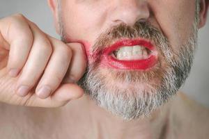 bebaarde boze man met rode lippenstift op zijn lippen foto