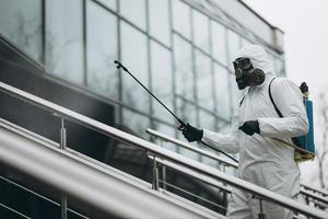 reiniging en desinfectie in het stadscomplex te midden van de coronavirusepidemie professionele teams voor desinfectie-inspanningen infectiepreventie en controle van epidemisch beschermend pak en masker foto