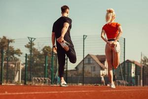 meisje en een jongen doen een warming-up voor sportoefeningen in het schoolstadion foto