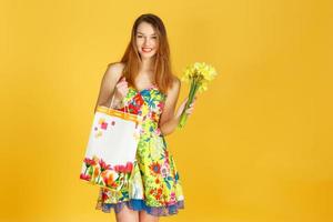 portret van jonge gelukkig lachende vrouw met boodschappentassen tegen gele muur foto
