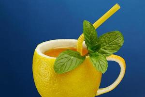 een kopje thee gemaakt van natuurlijke citroen met muntblaadjes. creatieve compositie rond het thema natuurlijke thee foto