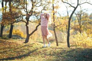 portretten van een charmant roodharig meisje met een schattig gezicht. meisje poseren in herfst park in een trui en een koraalkleurige rok. in de handen van een meisje een geel blad foto