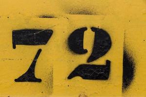 zwart nummer 72 stencil geschilderd op gele achtergrond foto