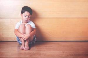 verdrietig kind zittend op de vloer foto