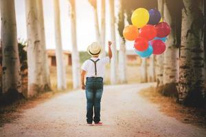 nadenkende jongen met ballonnen in het veld foto