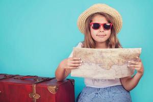 klein meisje met koffer en kaart foto