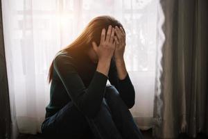 vrouw zit depressief bij het raam en angst kopieer ruimte. foto