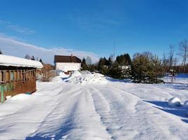 winterdag in het Russische dorp sneeuwput blauwe lucht foto