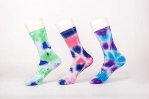 drie paar sokken van verschillende kleuren en stijlen zijn op de voetvorm op een witte achtergrond gehuld foto
