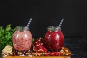 vers bereide smoothies van banaan met granaatappel en banaan met braambes in fles. dieet, gezonde levensstijl foto