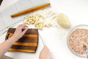 zelfgemaakte dumplings in de keuken zonder versieringen. dumplings maken met varkensgehakt, rundvlees en kip foto