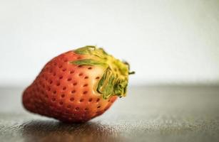 een close-up van een enkele rode aardbei op een tafel foto