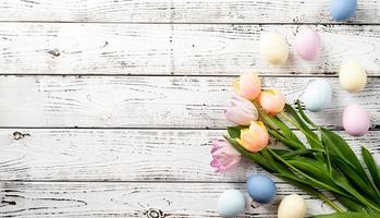 Pasen achtergrond met eieren en tulpen op witte houten achtergrond, bovenaanzicht plat lag foto