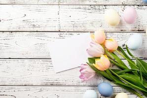 Pasen achtergrond met eieren en tulpen op witte houten achtergrond, bovenaanzicht plat lag foto