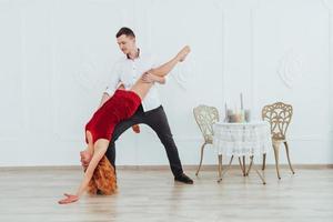 jonge mooie vrouw in een rode jurk en een man dansen, geïsoleerd op een witte achtergrond. foto