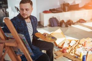 ontworpen door kunstenaar man afwerking van zijn meesterwerk houdt een borstel in de hand. foto