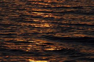 zon weerkaatst de golven bij zonsopgang foto