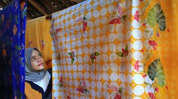 een vrouw die gekleurde batikdoek droogt, direct in de zon, pekalongan, indonesië, 7 maart 2020 foto