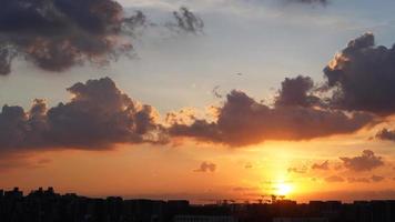 het prachtige uitzicht op de zonsondergang met het silhouet en de kleurrijke wolkenlucht in de stad foto