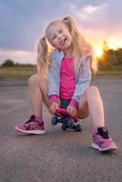 klein meisje zittend op de skate board foto