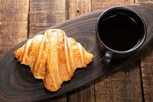 ontbijt eten koffie en croissant op geïsoleerde houten tafel. foto