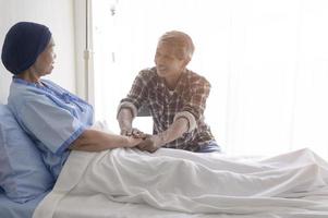 senior man op bezoek bij kankerpatiënt vrouw met hoofddoek in ziekenhuis, gezondheidszorg en medisch concept foto