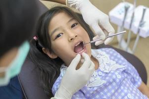 een klein schattig meisje met tanden onderzocht door tandarts in tandheelkundige kliniek, tandencontrole en gezond gebit concept foto