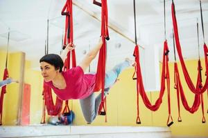 jonge mooie vrouw die yoga beoefent met een hangmat in de lichte studio. het concept van mentale en fysieke gezondheid. foto