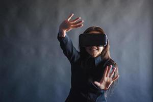 gelukkige vrouw op een zwarte achtergrond in de studio krijgt de ervaring van het gebruik van een vr-bril virtual reality-headset. foto