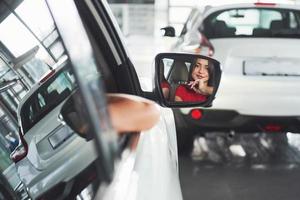 vrouw in auto binnen houdt wiel ronddraaiend glimlachend kijkend naar passagiers op de achterbank idee taxichauffeur tegen zonsondergang stralen licht glans hemel concept examen voertuig - tweede huis het meisje foto