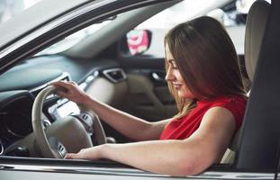 vrouw in auto binnen houdt wiel ronddraaiend glimlachend kijkend naar passagiers op de achterbank idee taxichauffeur tegen zonsondergang stralen licht glans hemel concept examen voertuig - tweede huis het meisje foto