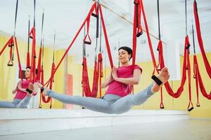 jonge mooie vrouw die yoga beoefent met een hangmat in de lichte studio. het concept van mentale en fysieke gezondheid. foto