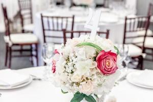 fancy tafel set voor het diner met bloem samenstelling in restaurant, luxe interieur achtergrond. bruiloft elegante banketdecoratie en items voor eten geregeld door cateringservice op witte tafel. foto