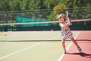 schattig meisje dat tennis speelt en poseert voor de camera foto