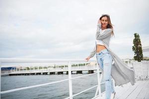 portret van een gelukkig jong meisje in een stijlvolle jurk in de buurt van het water. foto