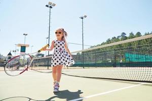 schattig meisje dat tennis speelt en poseert voor de camera foto