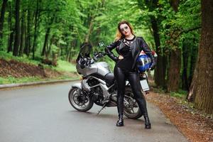 een aantrekkelijk sexy meisje op een sportmotor die buiten poseert foto