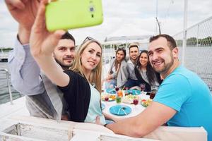 gelukkige jonge vrienden zaten aan een tafel en picknickten buiten. foto