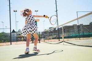 schattig meisje dat tennis speelt en poseert voor de camera foto