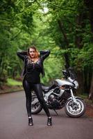 een aantrekkelijk sexy meisje op een sportmotor die buiten poseert foto