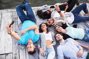 groep mooie jonge mensen die selfies maken die op de pier liggen, de beste vrienden van meisjes en jongens met plezierconcept creëert emotioneel leven van mensen foto