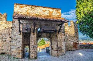 Brescia, Italië, 11 september 2019 stenen muur met kantelen en ophaalbrugpoort van middeleeuws kasteel Brescia foto