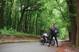 een aantrekkelijk sexy meisje op een sportmotor die buiten poseert foto