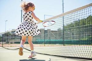 schattig meisje dat tennis speelt en poseert voor de camera foto