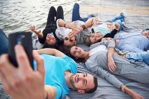 portret van gelukkige jonge vrienden op de pier aan het meer. terwijl u geniet van de dag en selfie doet. foto