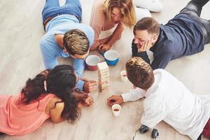 groep creatieve vrienden zitten aan houten tafel. mensen die plezier hebben tijdens het spelen van een bordspel foto