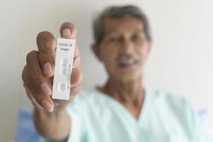 een Aziatische geduldige man toont de resultaten van de covid-19-test in het ziekenhuis foto