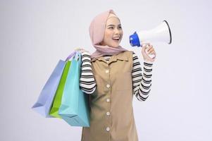 jonge mooie moslimvrouw in pak met kleurrijke boodschappentassen op een witte achtergrond studio foto
