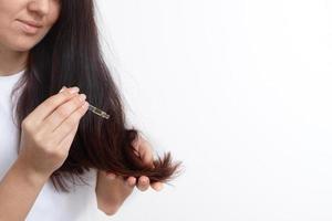 jonge vrouw met lang haar en een pipet in haar hand. haarbehandeling en verzorging. kopieer ruimte foto