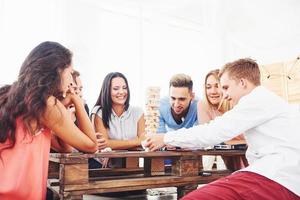 groep creatieve vrienden zitten aan houten tafel. mensen die plezier hebben tijdens het spelen van een bordspel foto